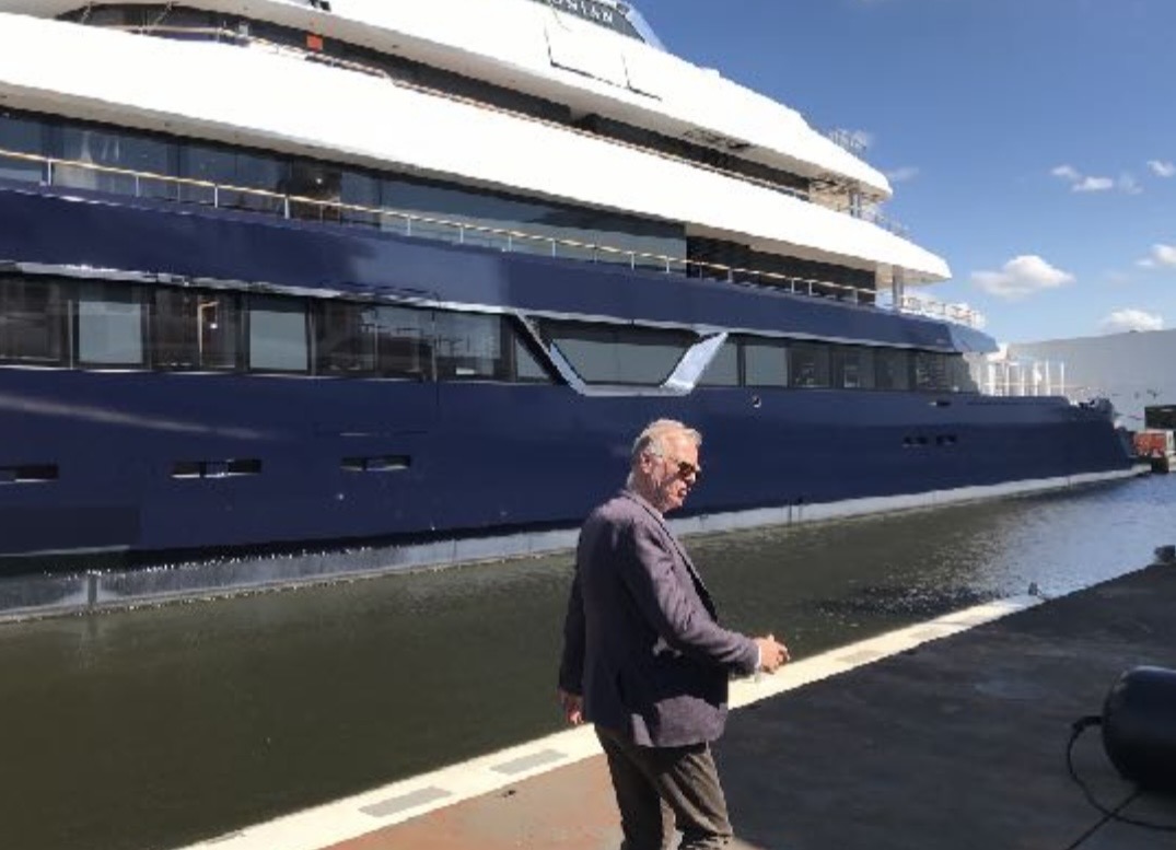 Feadship superyacht at the Amsterdam shipyard with a man in the foreground
